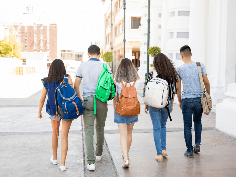 Teenage schoolgirls with backpacks walking together
