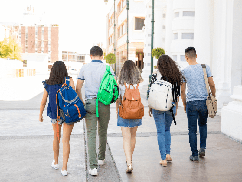 Teenage schoolgirls with backpacks walking together